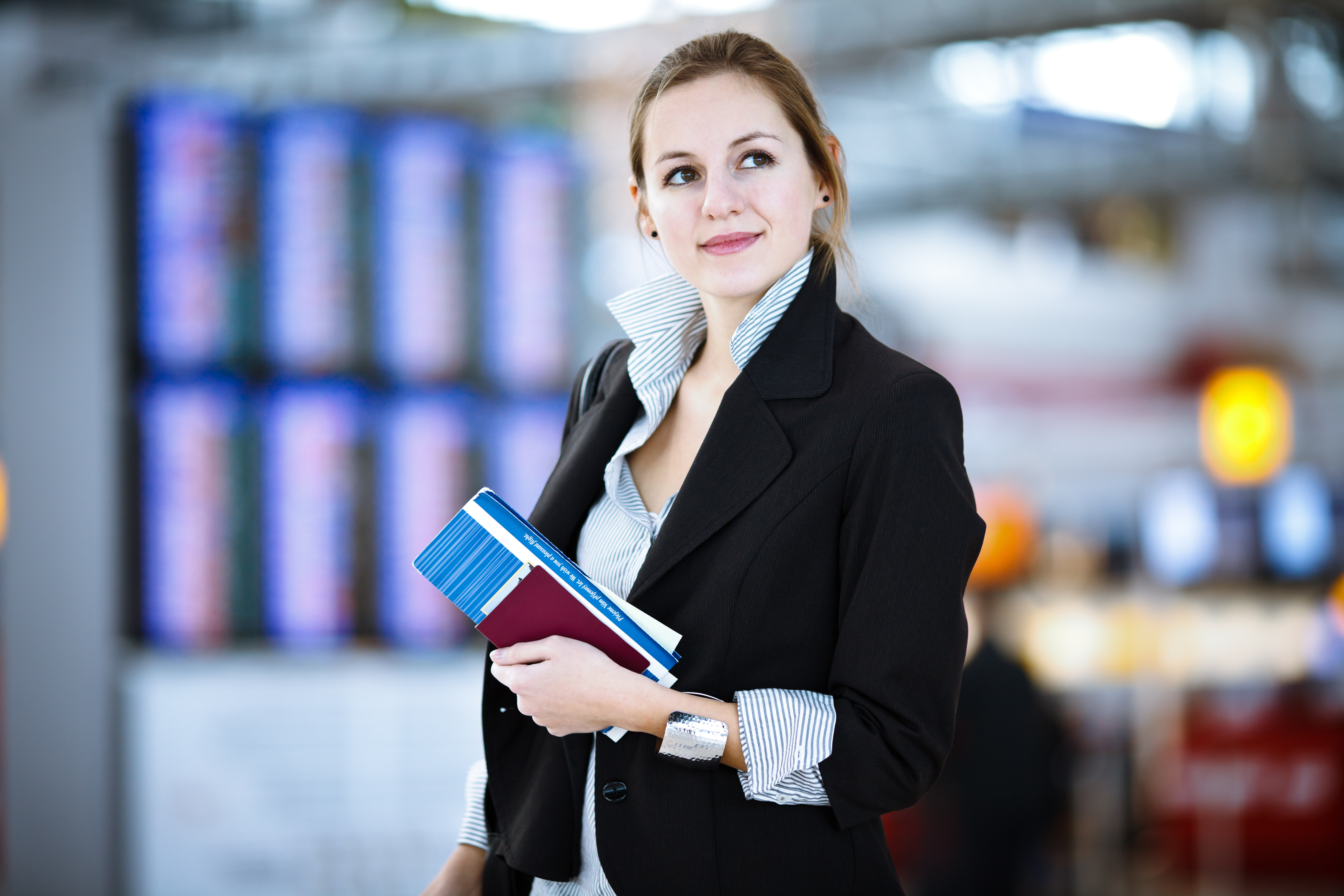 Female student holds her travel documents at the airport as she prepares for her group to travel.